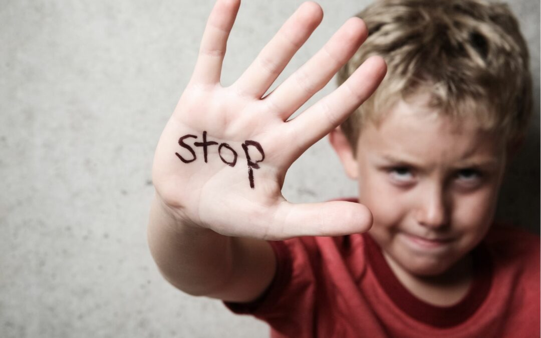 Enfant montre sa main où il est écrit Stop