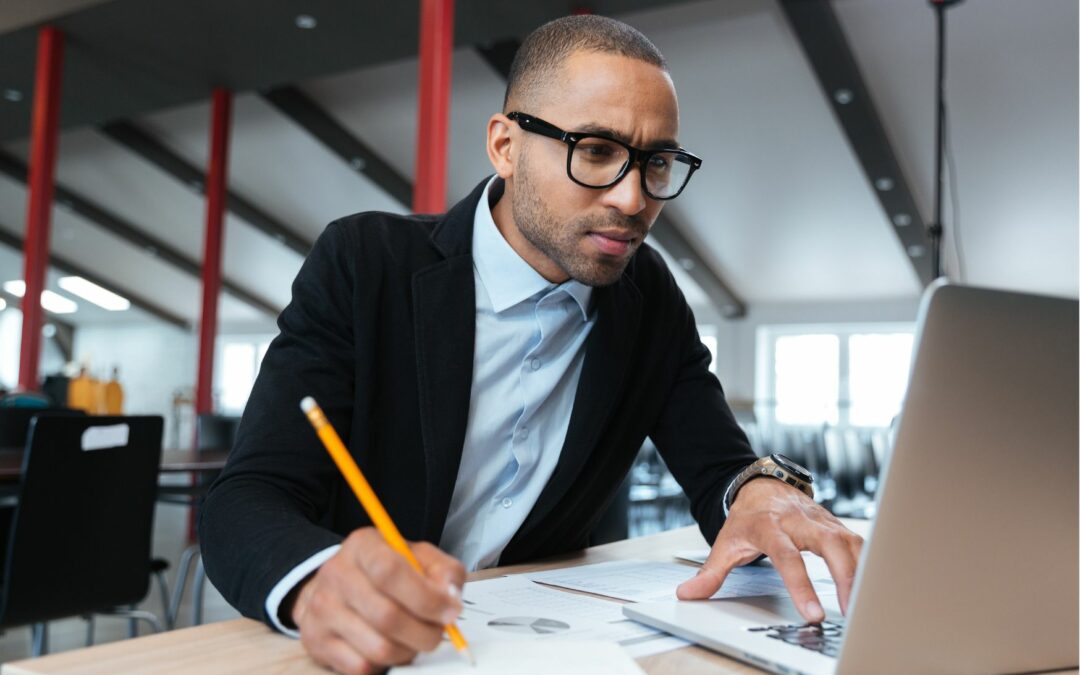 enseignant qui regarde son ordinateur tout en écrivant