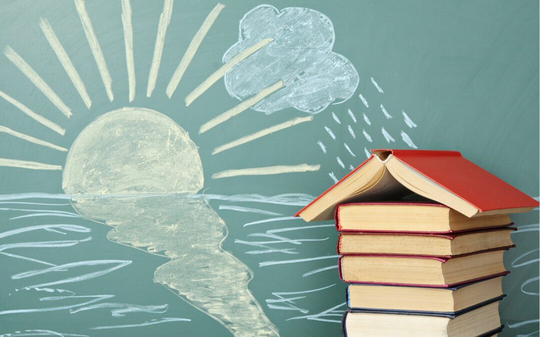 pile de livres formant bâtiment et tableau avec soleil et mer dessinés à la craie