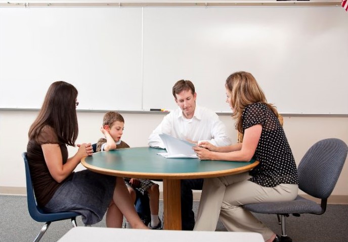 parents élève enseignante autour d'une table