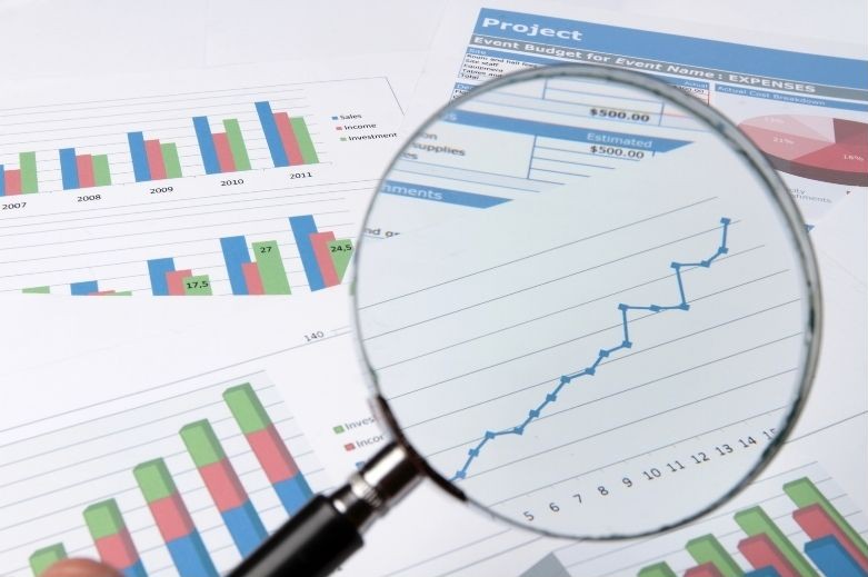 une loupe qui examine divers documents, dont des graphiques